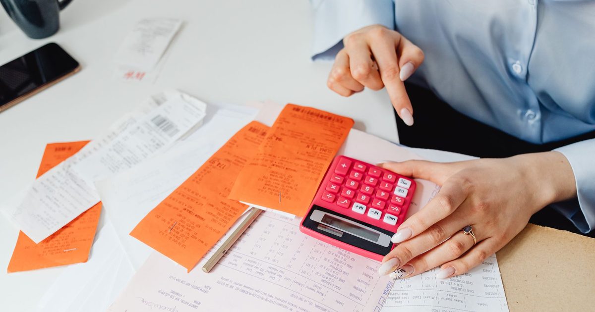 Hands with a calculator, receipts and handwritten figures on a desk