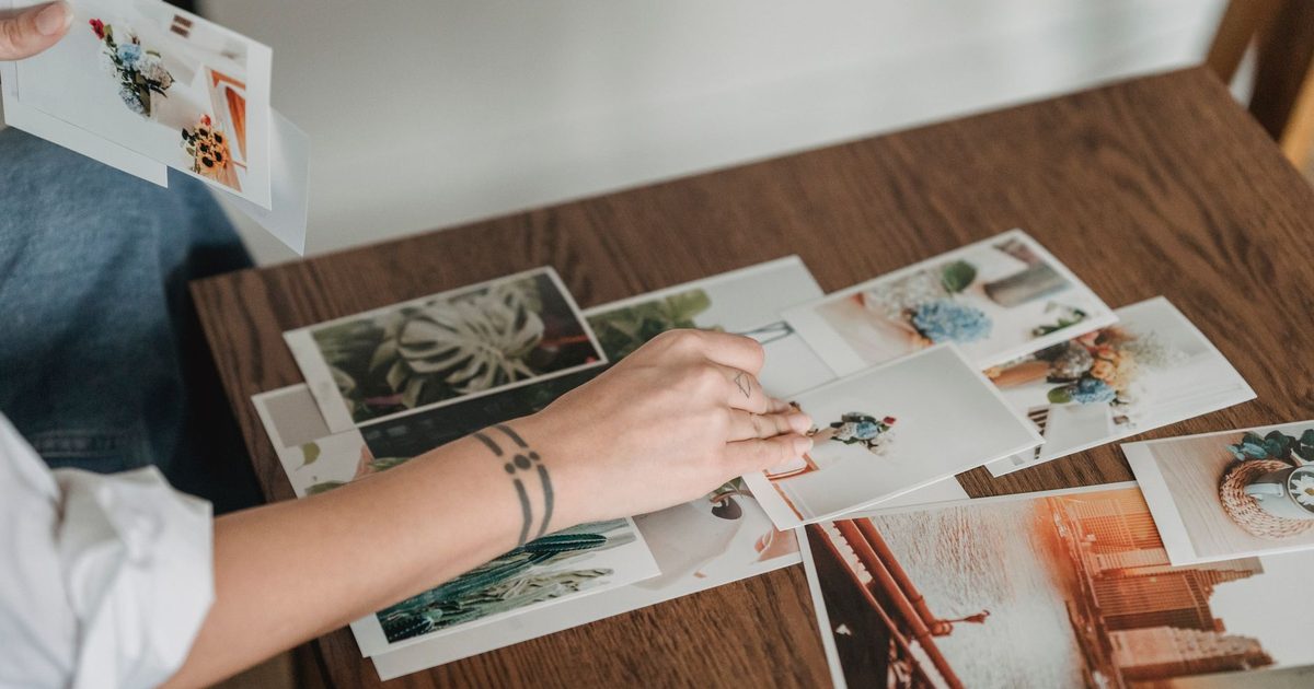 Hand picking one print from many spread across a wooden table