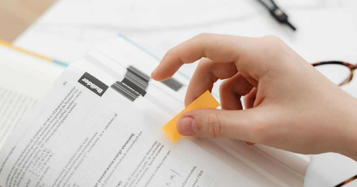 Hand placing a sticky tab on a printed page already marked with flags