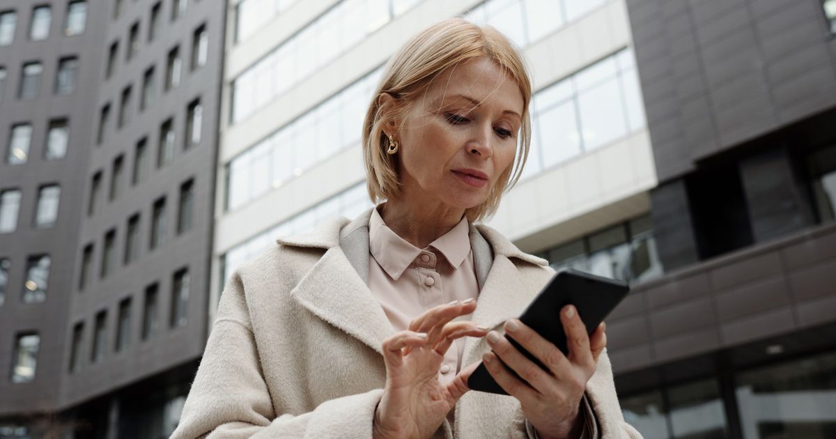 Woman in a coat checking her phone on a city street