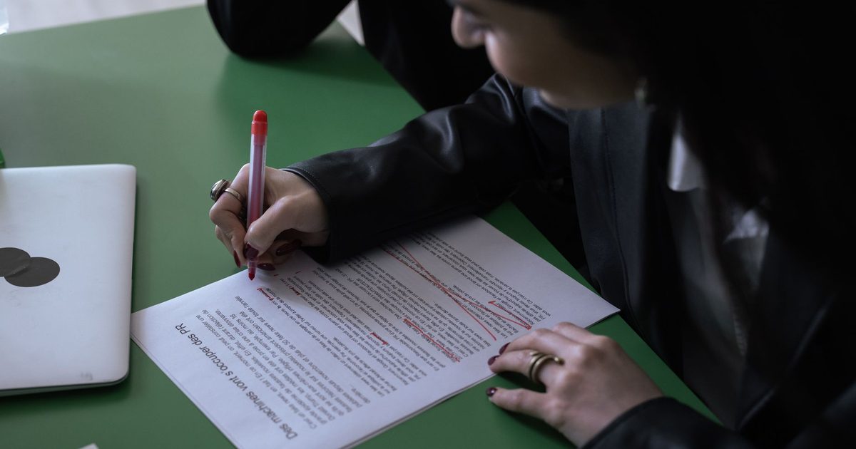Person marking up a printed document with a red pen