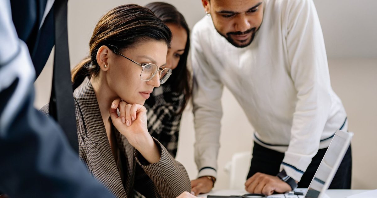 Three colleagues looking together at one laptop screen