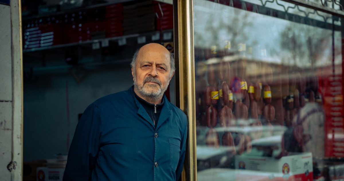 Older shopkeeper standing in the doorway of his own shop